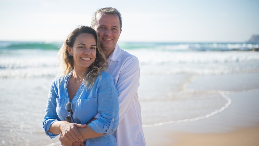 Smiling couple embracing on a sunny beach, a scene about trust and how to predict infidelity before commitment