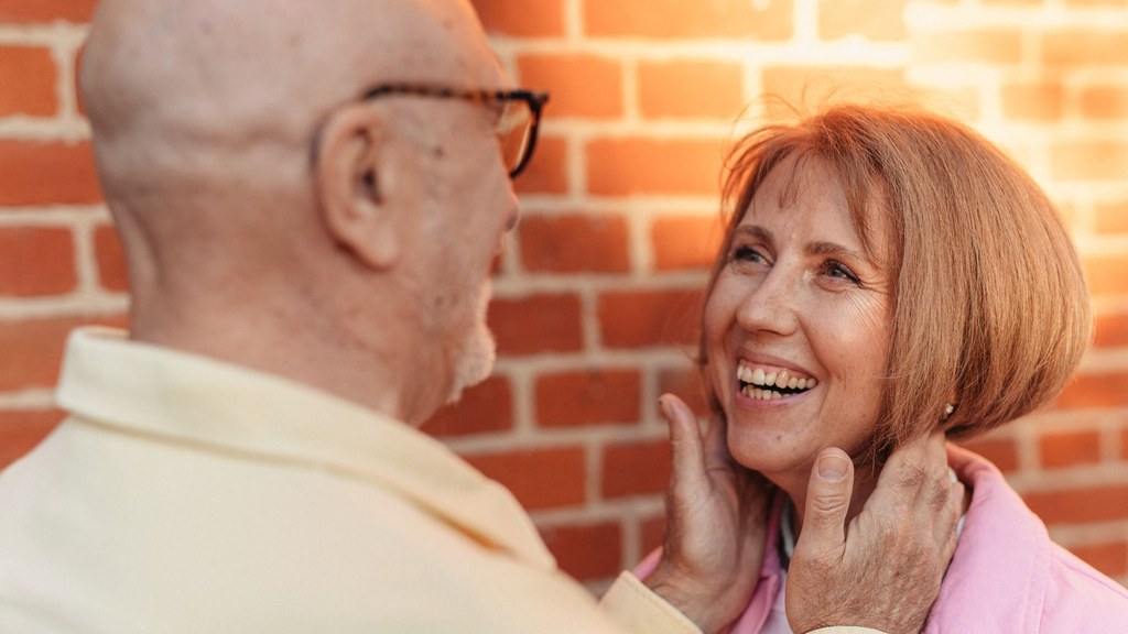 Laughing older woman touching her partner's face tenderly, showing companionship without rushing into marriage