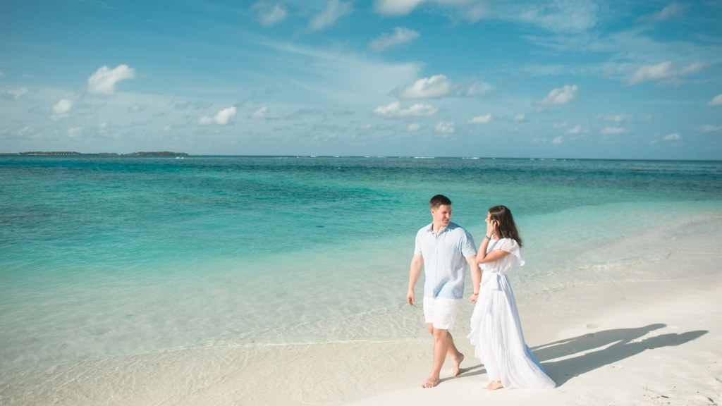 Couple on a beach holiday walking hand in hand along a turquoise shoreline