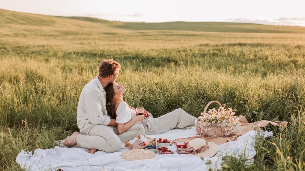 Man wrapping his arms around his partner on a picnic blanket, sharing body temperature and closeness