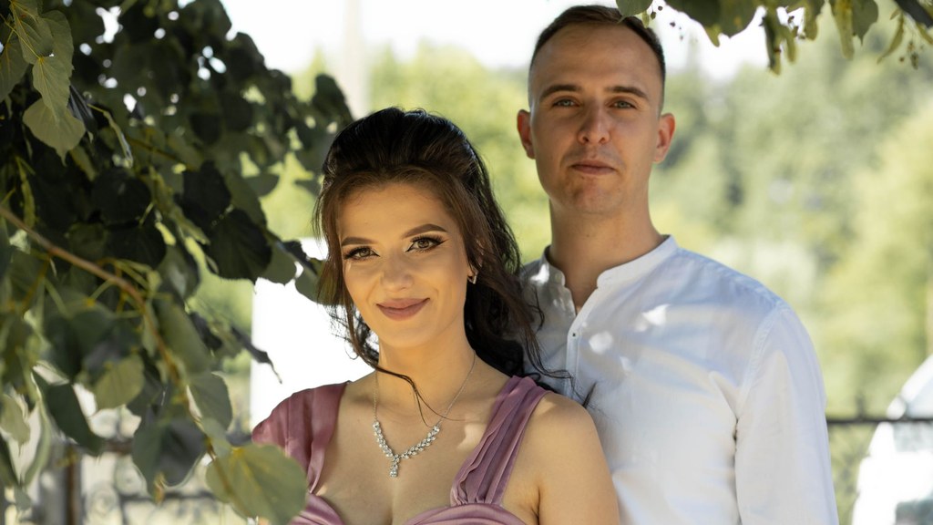 Smiling couple standing close under green leaves, showing the trust that breast self-examination talks need
