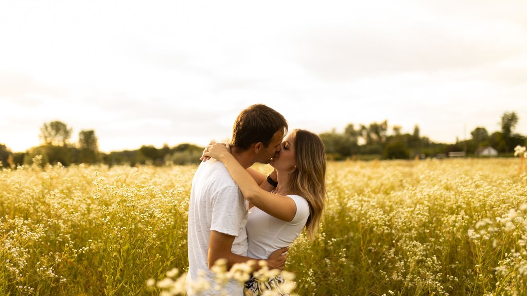 Couple kissing in a sunny flower field, accepting cellulite and natural bodies in a loving relationship