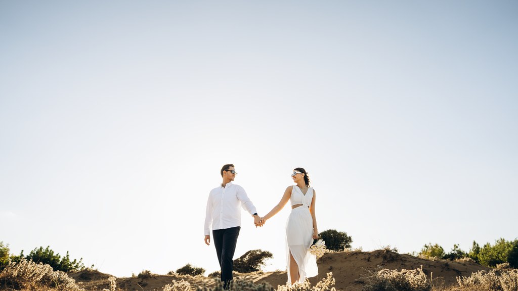 Couple holding hands on a sunny hill by the sea, a scene about intimacy and female pleasure in a committed relationship