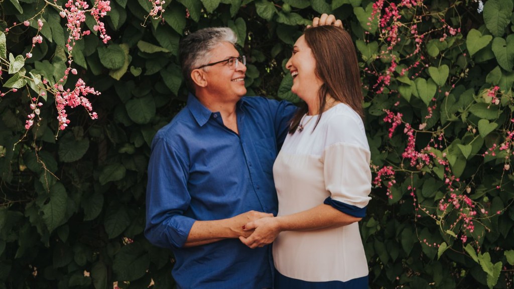 Couple laughing and holding hands among flowers, a warm moment of open conversation about desire at midlife