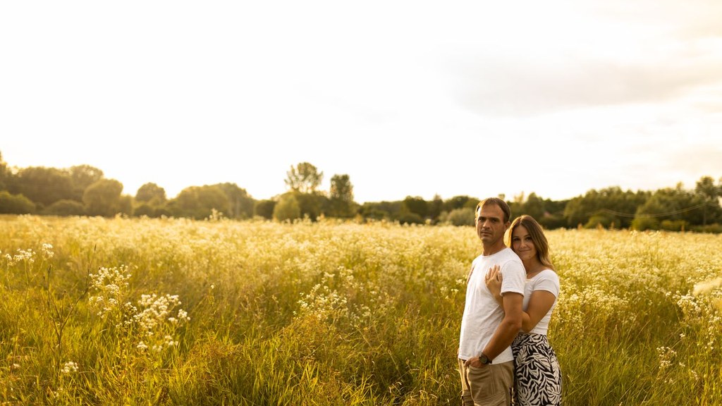 Couple standing close together in a golden meadow, calm affection that leaves room for distance, unlike love addiction