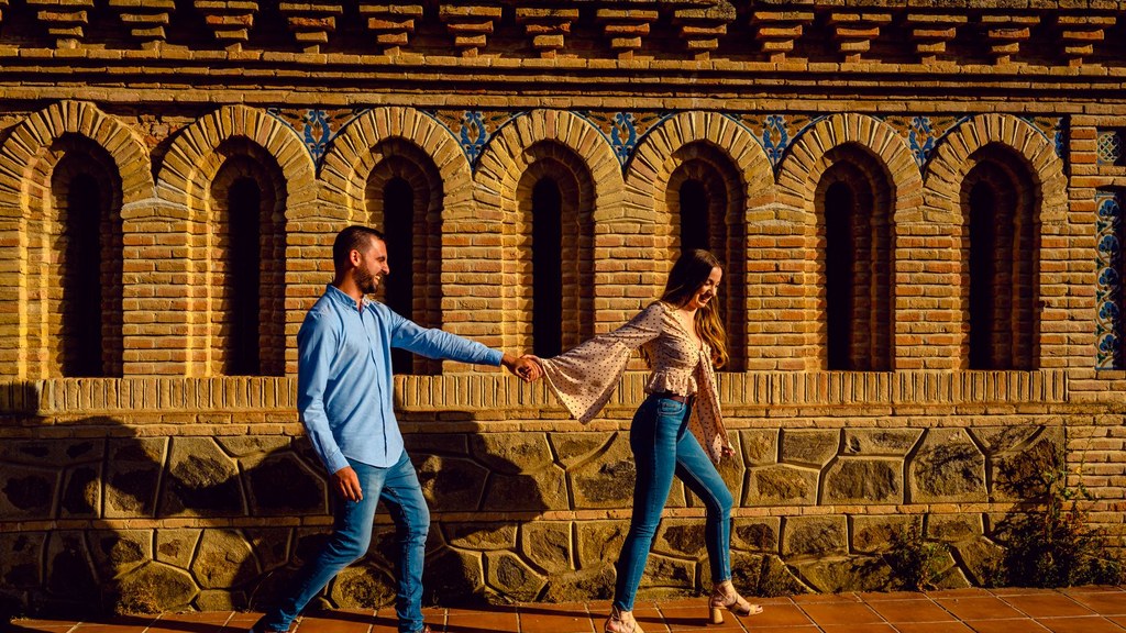 Couple walking hand in hand along a sunlit wall, talking calmly about how to end a relationship respectfully
