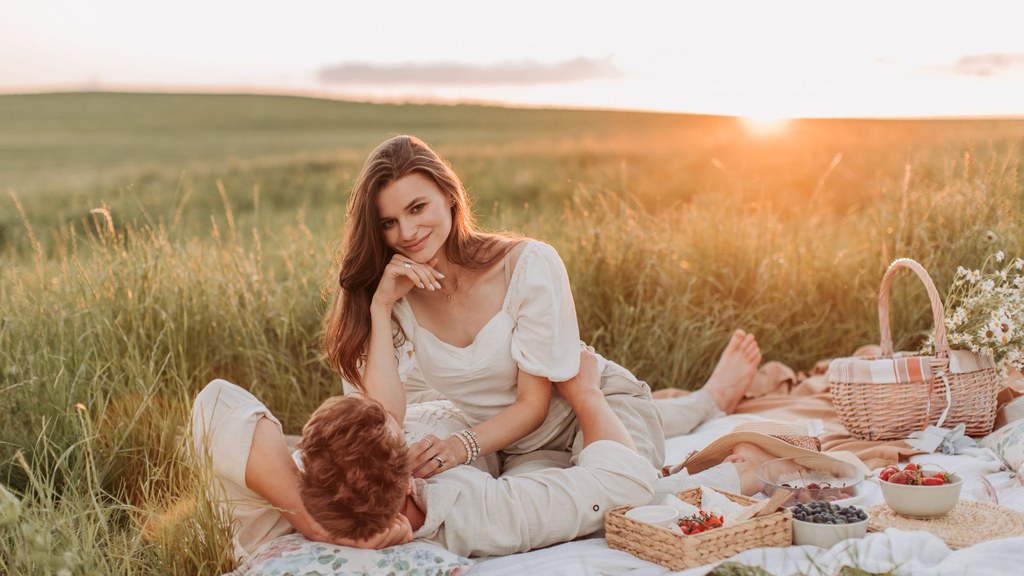 European couple relaxing together on a picnic blanket in a summer field with fresh food, illustrating diet and sexual health