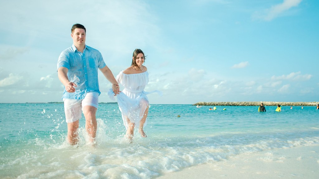 European couple running hand in hand on a sunny beach during their first trip together