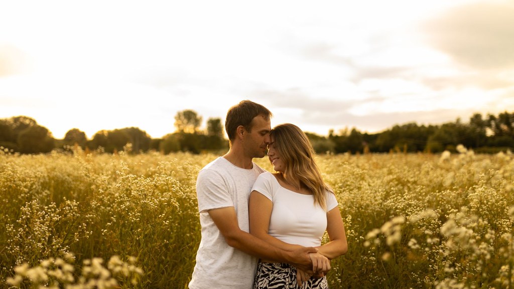 Gratitude in relationships: a couple embracing in a sunlit summer meadow, foreheads touching