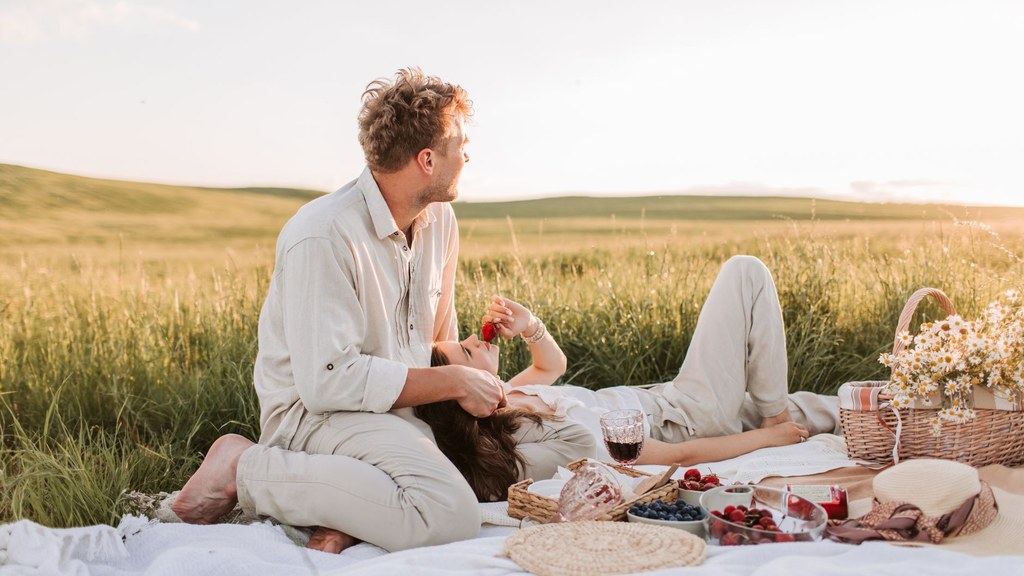 Relaxed couple at a sunny countryside picnic, showing the ease that skin confidence after laser skin treatment can bring