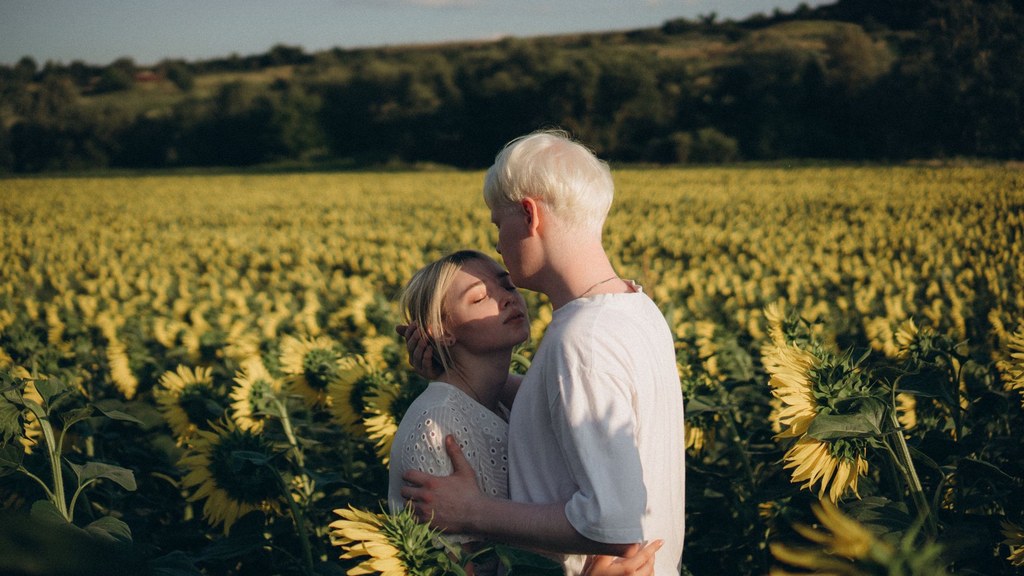 Young couple embracing in a sunflower field at golden hour, closeness that long-distance couples protect