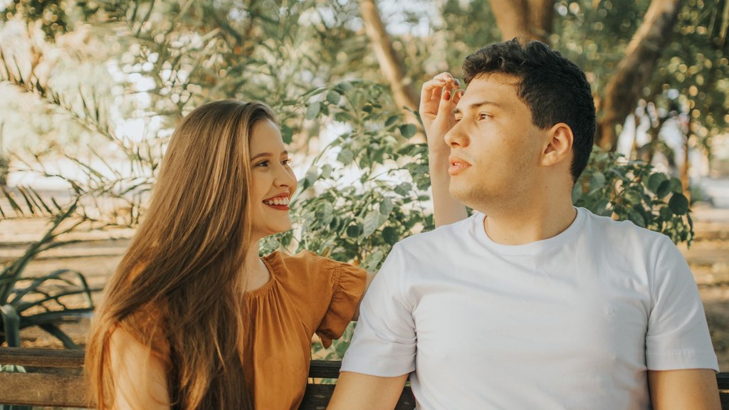 Young couple laughing on a park bench; a simple date and money in relationships