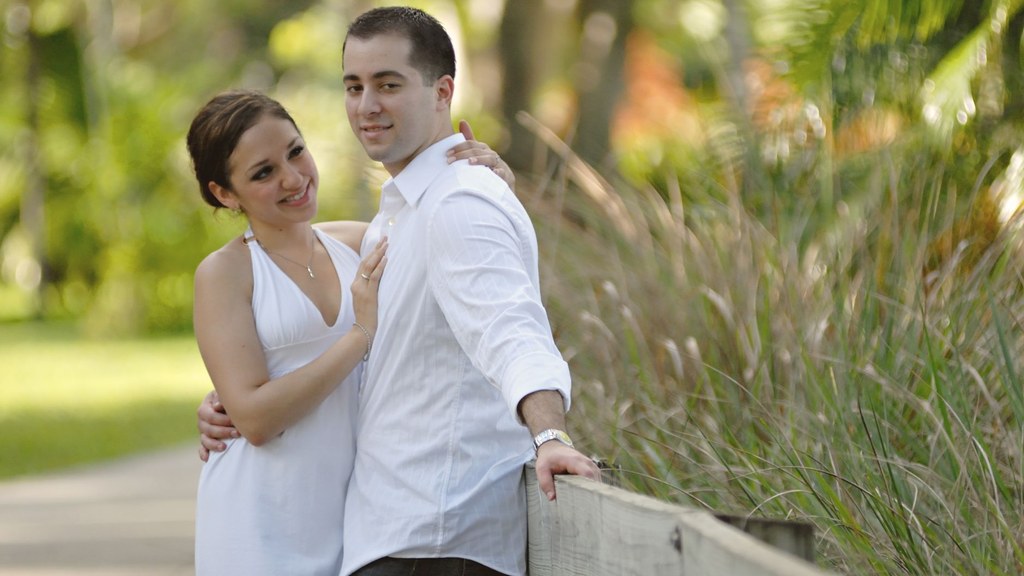 Smiling couple in white embracing in a sunny garden, relaxed about ejaculation time and intimacy