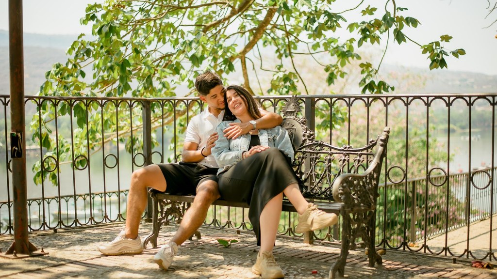 Couple cuddling on a garden bench with a sunny lake view, a tender moment that goes beyond sounds during sex