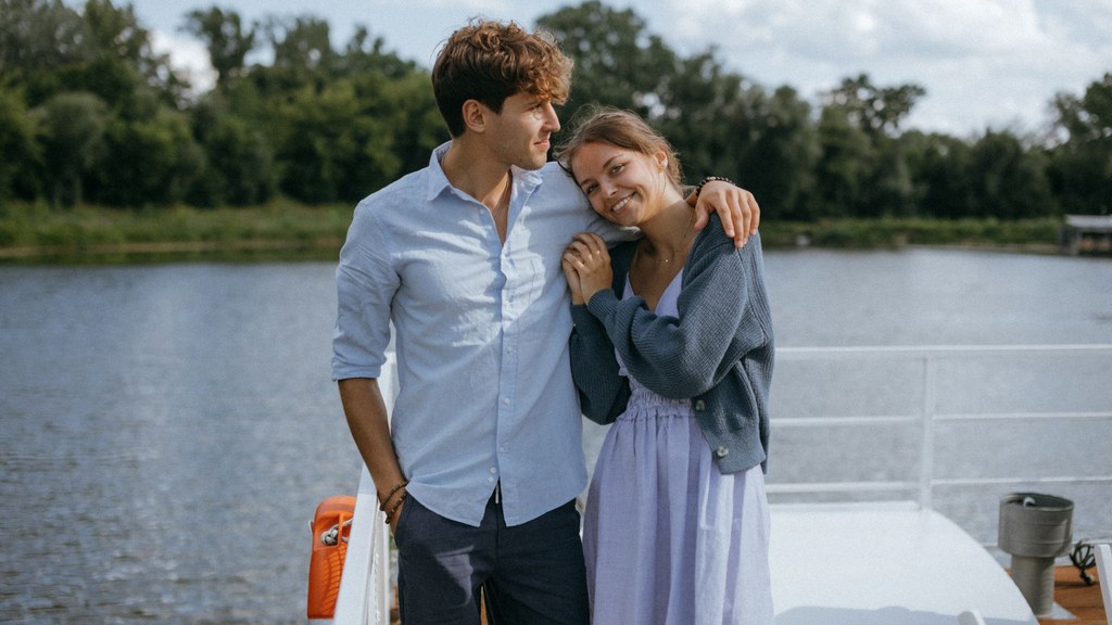 Young couple embracing by a river on a bright day, relaxed and open about sounds during sex and intimacy